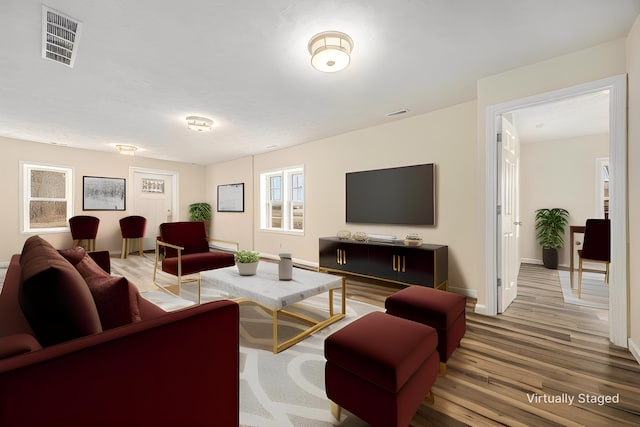 living room featuring light wood-style flooring, baseboards, and visible vents