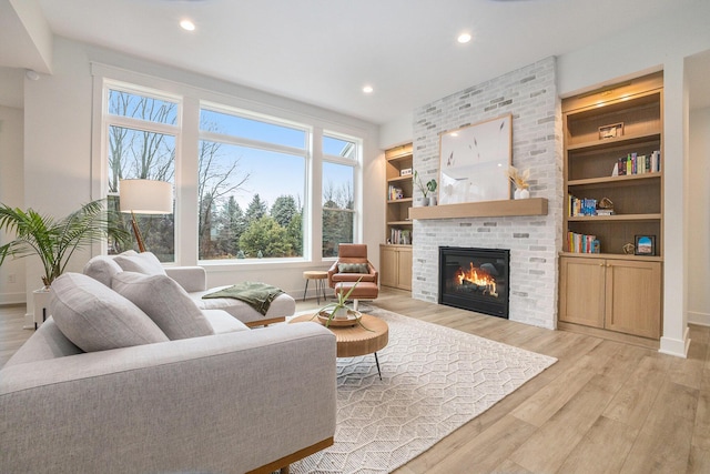 living room featuring a fireplace, recessed lighting, light wood-style floors, and baseboards