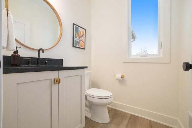 bathroom with baseboards, toilet, wood finished floors, and vanity