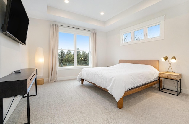 bedroom featuring a raised ceiling, baseboards, and light carpet