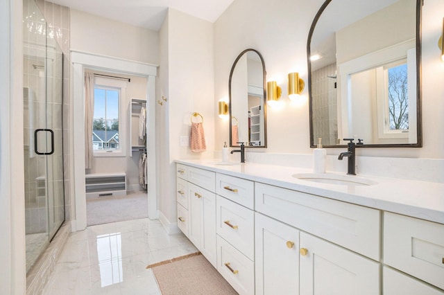 bathroom featuring a sink, a walk in closet, marble finish floor, and a shower stall