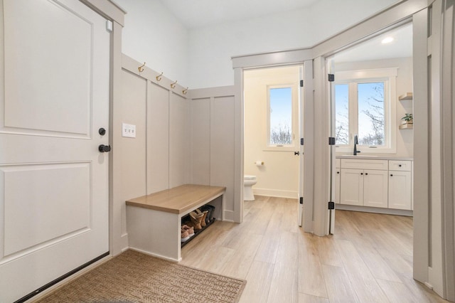 mudroom featuring light wood-style flooring, a wainscoted wall, and a sink