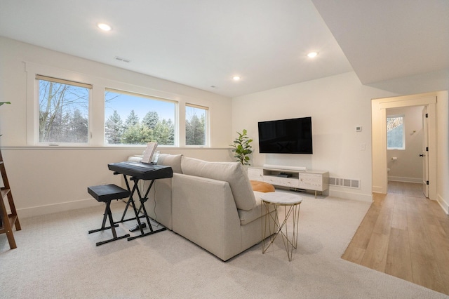 carpeted living area with recessed lighting, visible vents, and baseboards