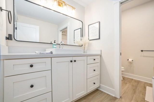 bathroom featuring toilet, vanity, baseboards, and wood finished floors