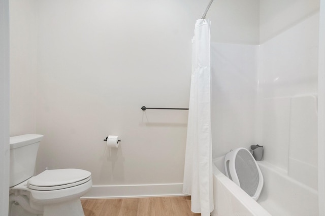 full bath featuring toilet, shower / bath combo, baseboards, and wood finished floors