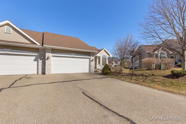 view of front of house with aphalt driveway, an attached garage, brick siding, and a shingled roof