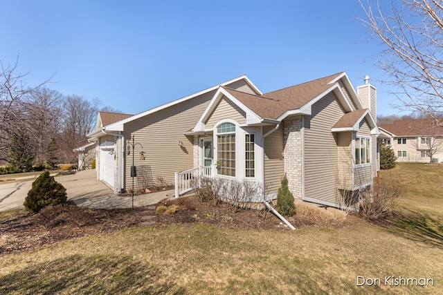 view of home's exterior featuring a yard, a shingled roof, a chimney, a garage, and brick siding