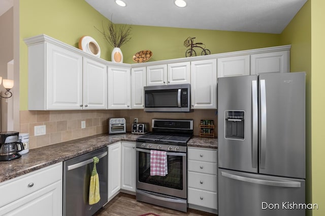 kitchen featuring decorative backsplash, dark countertops, appliances with stainless steel finishes, and white cabinets