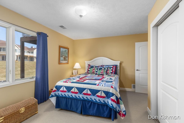 bedroom featuring multiple windows, visible vents, carpet floors, and a textured ceiling