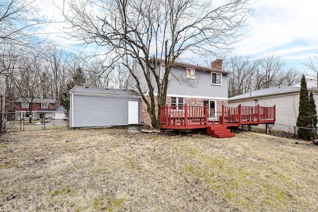 rear view of house featuring an outbuilding, a fenced backyard, a chimney, a deck, and a lawn