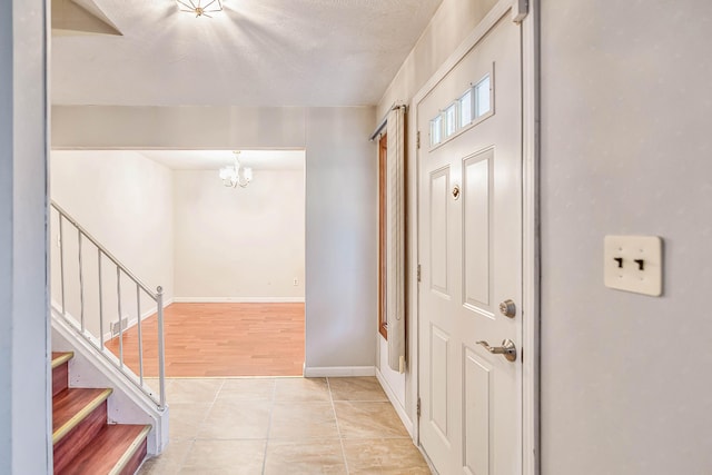 entrance foyer with stairway, light tile patterned floors, baseboards, and a chandelier