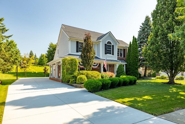 view of front facade featuring brick siding, concrete driveway, and a front lawn