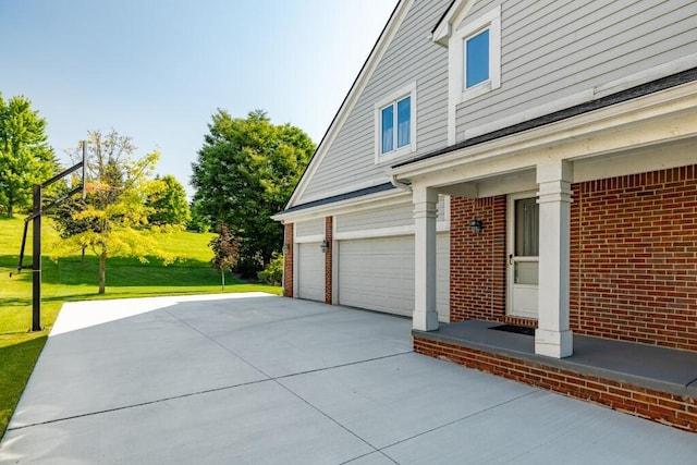 view of side of property with concrete driveway, a yard, brick siding, and an attached garage