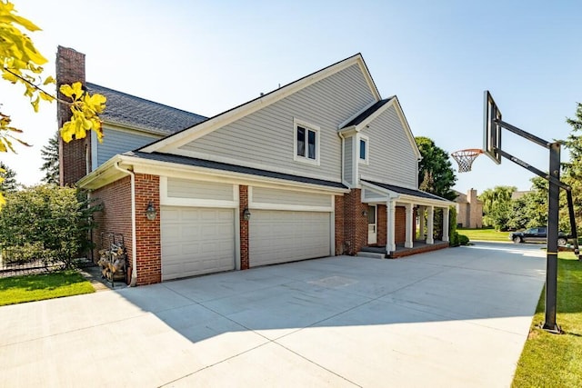 view of front facade featuring brick siding, a chimney, and concrete driveway