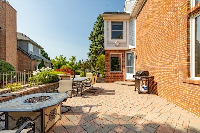 view of patio featuring fence, area for grilling, outdoor dining space, and an outdoor fire pit