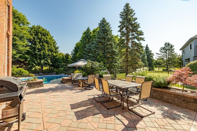 view of patio / terrace featuring outdoor dining space, a fenced backyard, a fenced in pool, and a grill