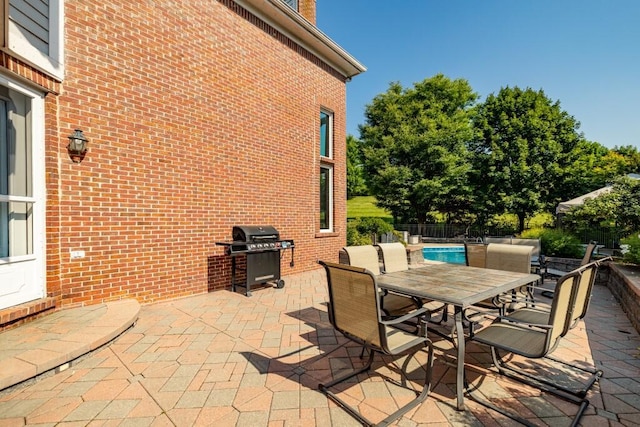 view of patio with area for grilling, outdoor dining space, and fence