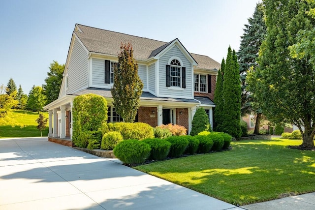 view of front facade featuring a front lawn, brick siding, and driveway