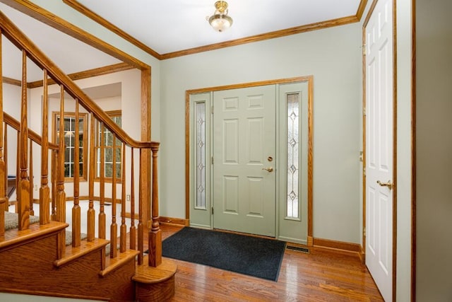 foyer with ornamental molding, stairs, baseboards, and wood finished floors