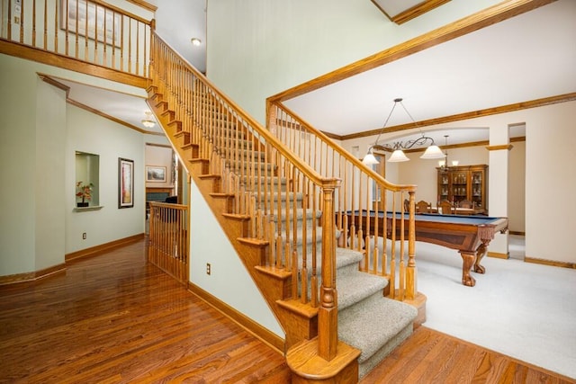 stairway with crown molding, wood finished floors, and baseboards