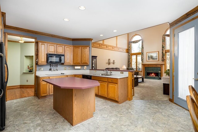 kitchen featuring a center island, light countertops, a peninsula, black appliances, and a sink