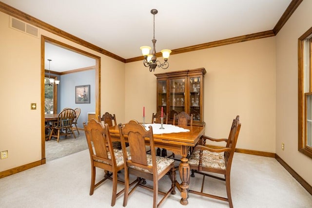 dining room with a notable chandelier, visible vents, light colored carpet, and ornamental molding