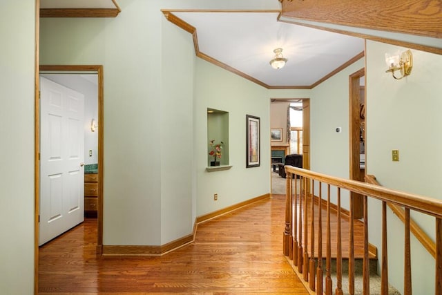 hallway featuring baseboards, wood finished floors, and ornamental molding