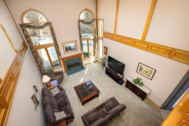 carpeted living area featuring a fireplace with flush hearth and a high ceiling