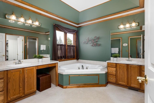 full bathroom with two vanities, a garden tub, and a sink