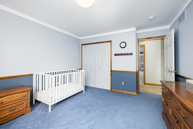 carpeted bedroom with a closet, visible vents, crown molding, and baseboards