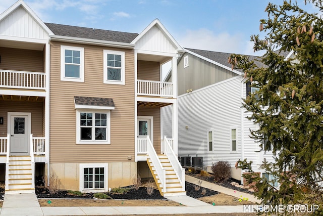 multi unit property with central AC unit, a shingled roof, and stairs