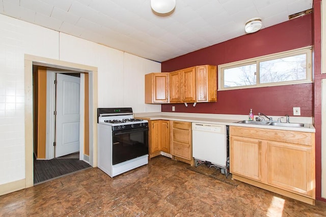 kitchen with light brown cabinets, light countertops, white dishwasher, gas stove, and a sink