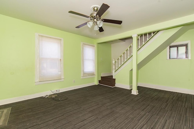 unfurnished living room with stairway, baseboards, and a ceiling fan