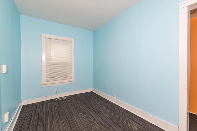 spare room featuring visible vents, baseboards, and dark wood-type flooring