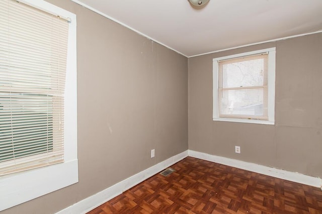 spare room featuring crown molding, baseboards, and visible vents