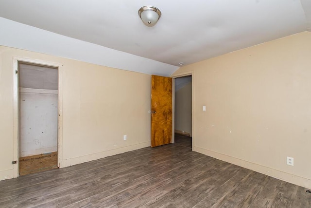 unfurnished bedroom featuring a closet, lofted ceiling, baseboards, and wood finished floors