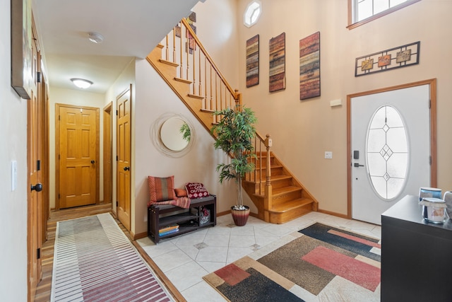 entryway with light tile patterned floors, stairway, and baseboards