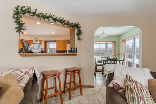 living area featuring arched walkways, recessed lighting, light wood-style flooring, and baseboards