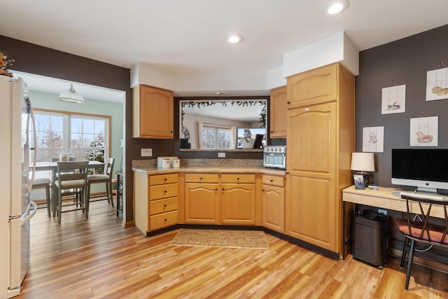 kitchen featuring light countertops, light wood-style floors, freestanding refrigerator, and a healthy amount of sunlight