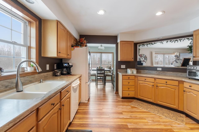 kitchen with light countertops, recessed lighting, light wood-style flooring, white dishwasher, and a sink