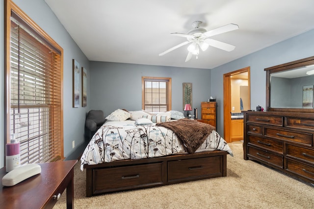 bedroom with light colored carpet, connected bathroom, and ceiling fan