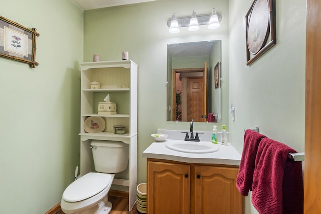 half bathroom featuring vanity, toilet, and baseboards