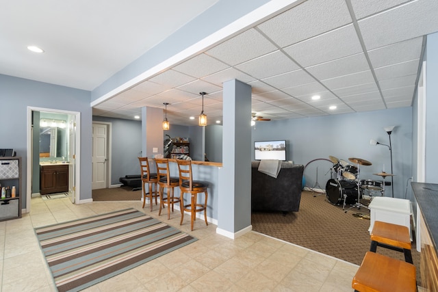 carpeted living room with recessed lighting, a bar, a paneled ceiling, and baseboards