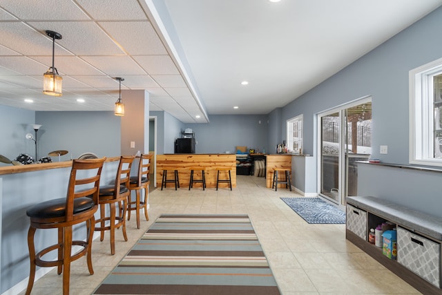 dining area featuring recessed lighting, a bar, a paneled ceiling, and baseboards