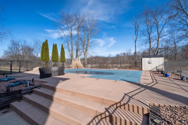 view of pool featuring an outbuilding, a fenced in pool, fence, a storage unit, and a patio area