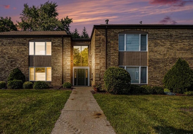 view of front of house featuring a yard and brick siding