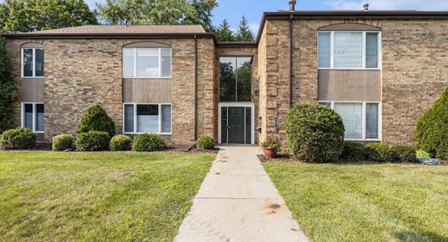 townhome / multi-family property with a front yard and brick siding