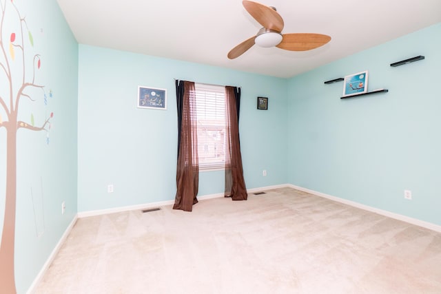 spare room featuring visible vents, a ceiling fan, baseboards, and light carpet