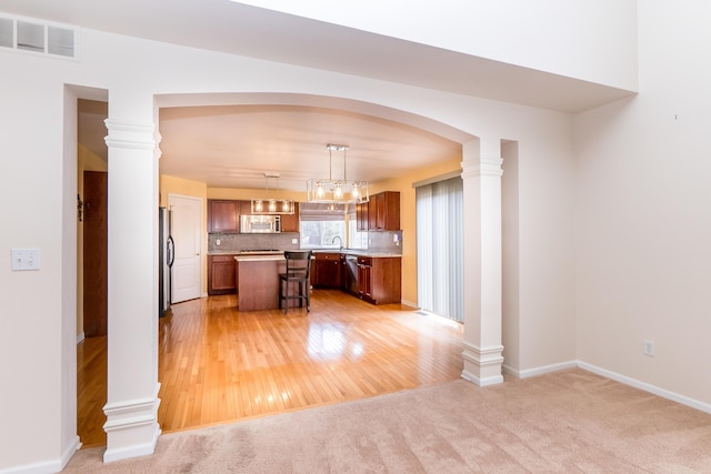 kitchen featuring a kitchen island, visible vents, stainless steel appliances, and ornate columns