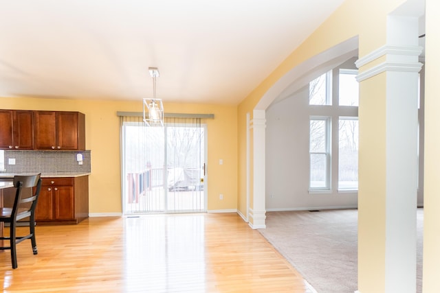 kitchen with arched walkways, tasteful backsplash, a healthy amount of sunlight, and ornate columns